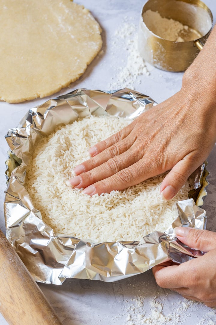 Adding weight to the pastry to keep it flat