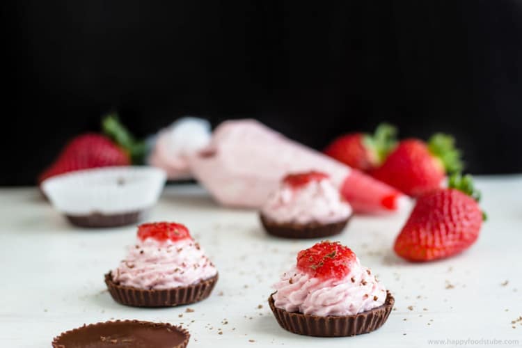 Mini chocolate cups with strawberry mousse filling and strawberry on top.