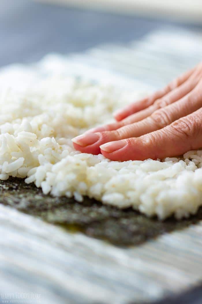 How to make Homemade Sushi Step 1 - Cover nori sheet with rice and press it down.