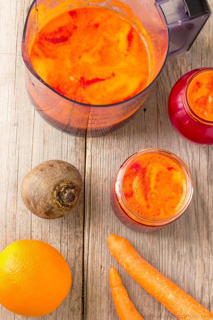 Homemade beet juice with carrots and oranges on the table.