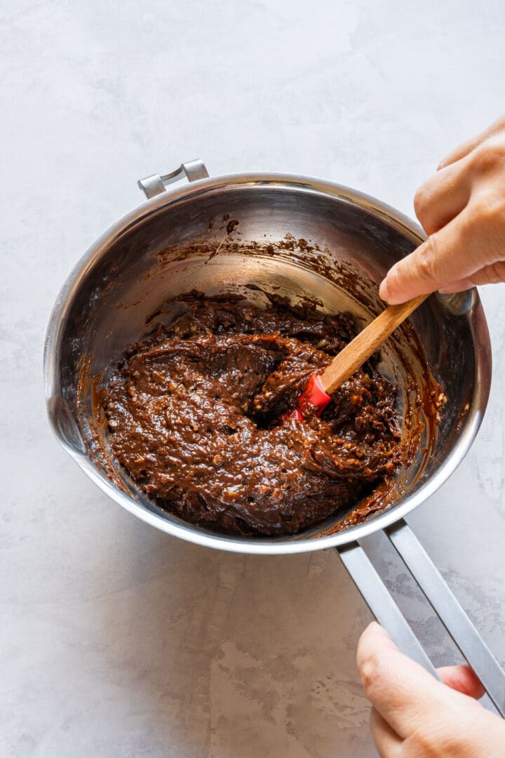 Thick truffle mixture being stirred in a metal bowl.