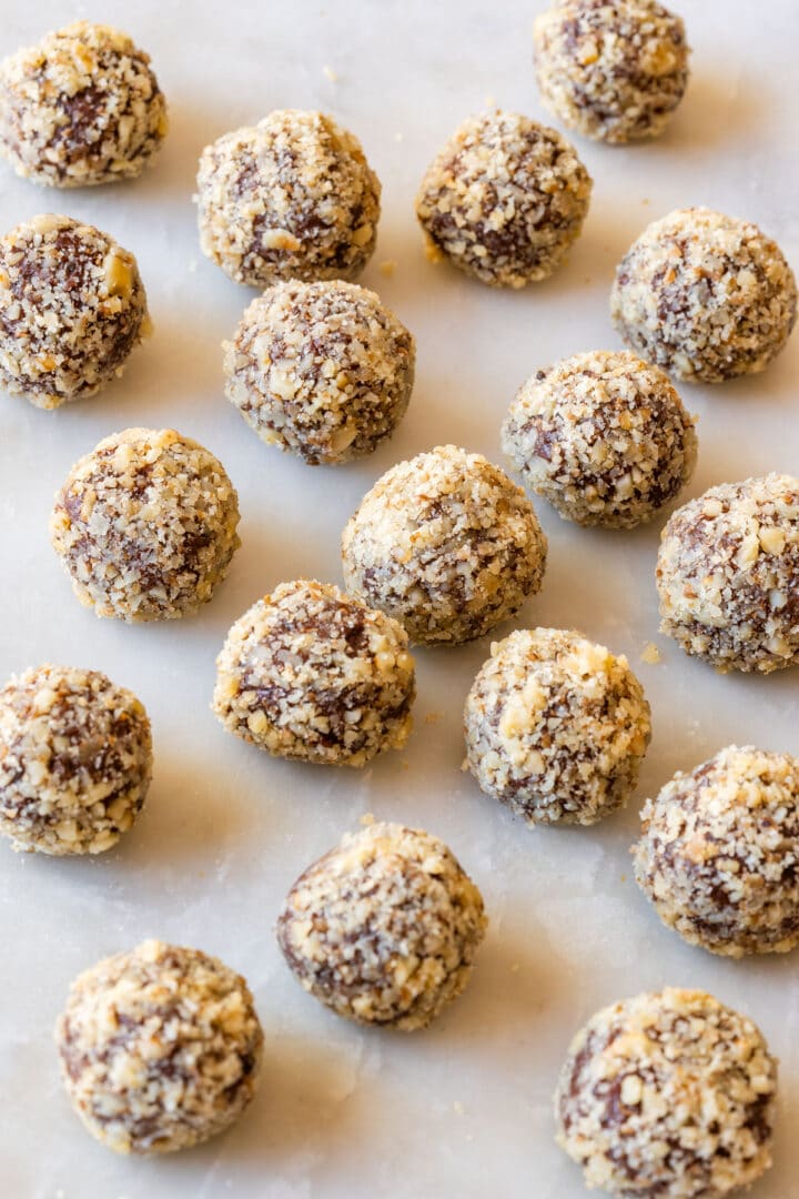 Walnut-coated chocolate truffles lined up on parchment paper.
