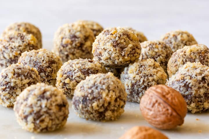 Plate of walnut-coated truffles with a whole walnut nearby.