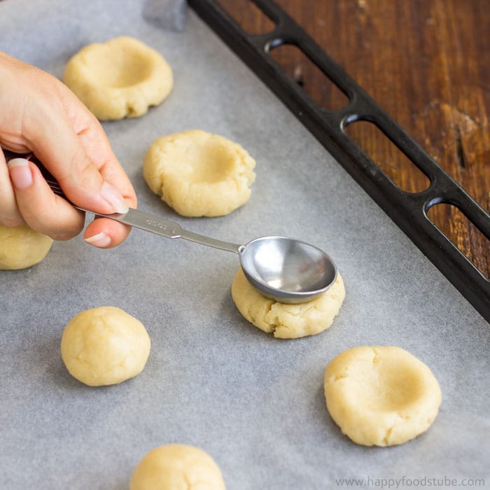 Pressing cookie dough down with thumb or the back of a dessert spoon.