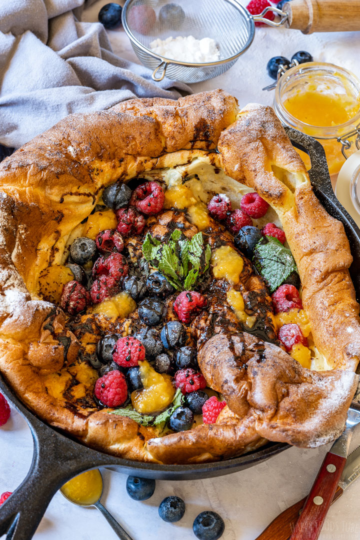 German pancake topped with bluebrries, raspberries and fruit jams