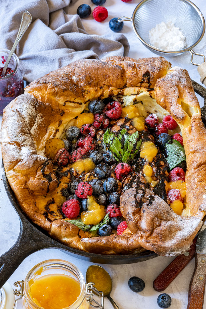 Dutch baby pancakes with frehs fruit and drizzled with chocolate sauce