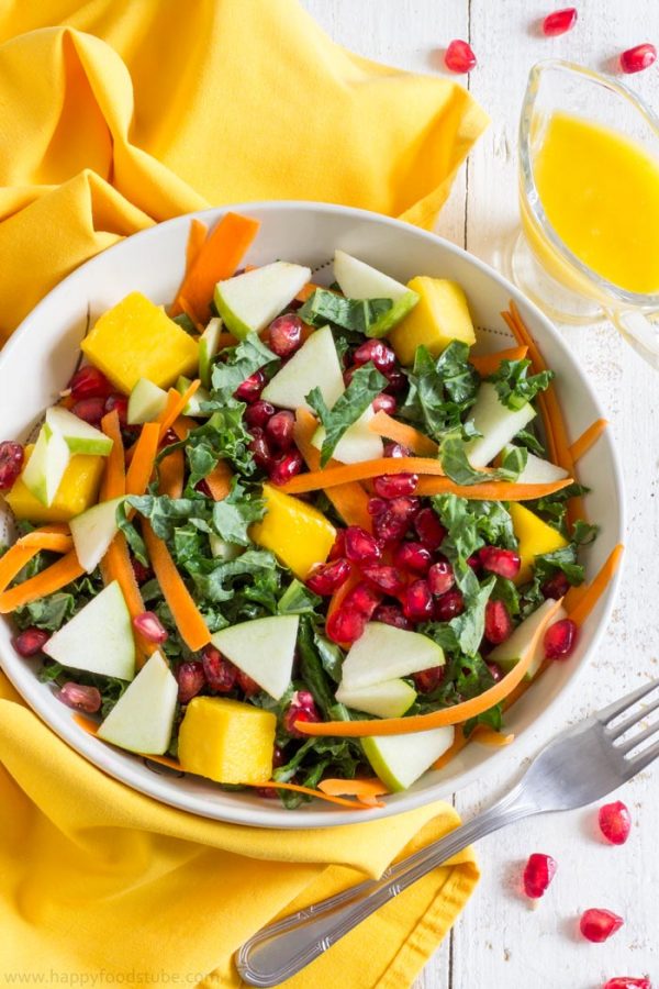 Kale salad with apple, carrot, mango and pomegranate, served with a jug of mango dressing.