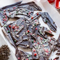 Overhead Christmas chocolate bark shards with red, green and white sprinkles on parchment.
