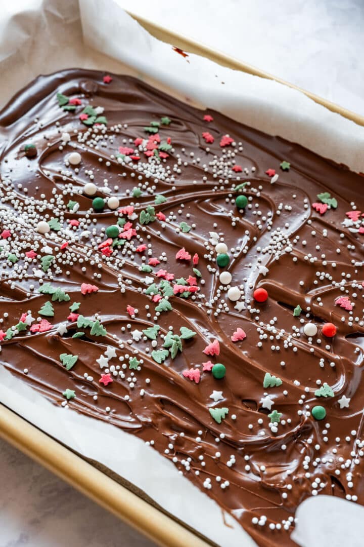 Close-up of melted chocolate topped with holiday sprinkles and nonpareils before setting.