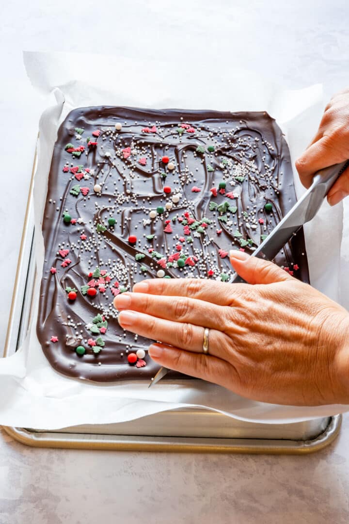 Cutting set chocolate bark on a baking sheet to make neat pieces.