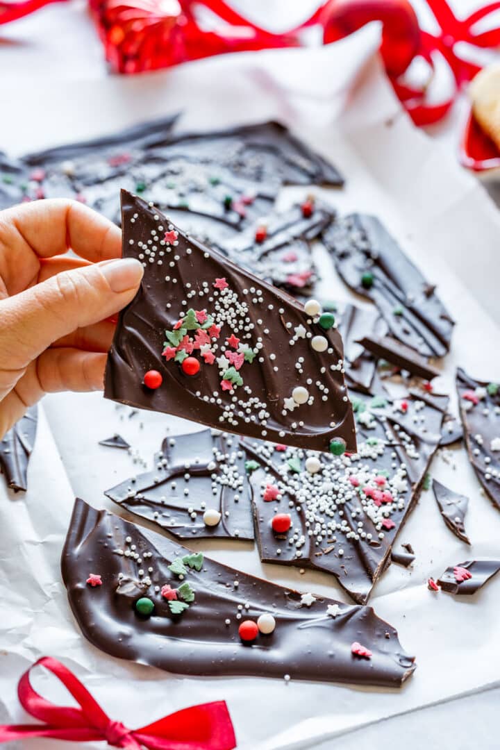 Hand holding a finished piece of Christmas bark with sprinkles.