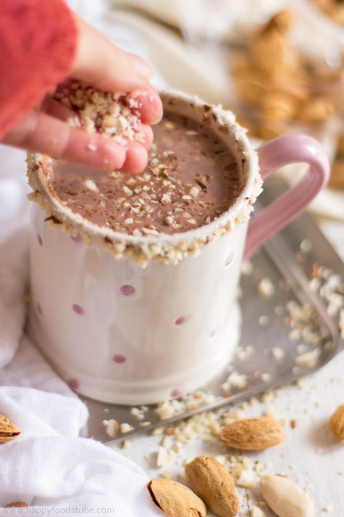 Topping hot cocoa with chopped almonds