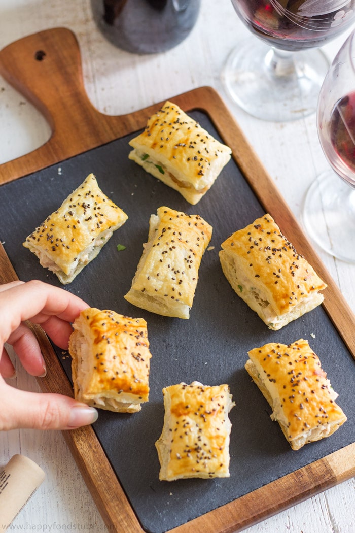 Taking bite-size mango chicken puff from a tray.