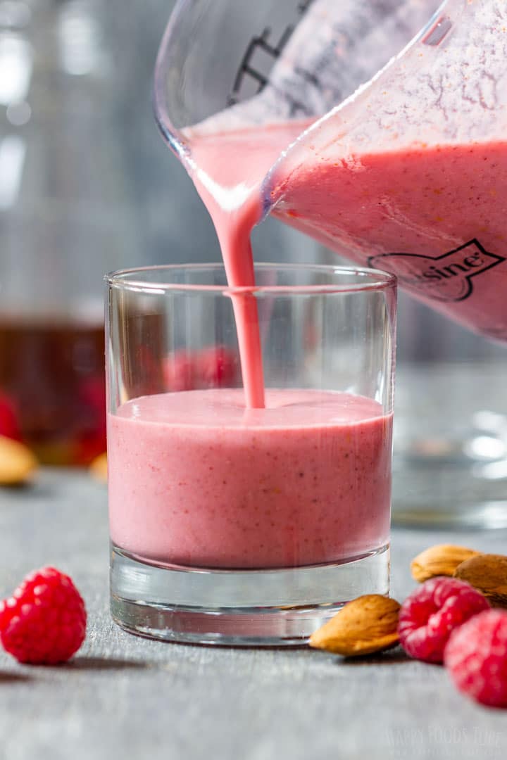 Pouring freshly made raspberry smoothie to the glass