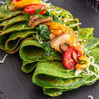 Green spinach crepes with sauteed mushrooms, cherry tomatoes, bell peppers, herbs, and cheese.