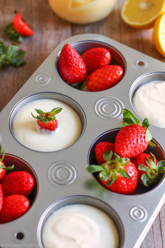 Muffin pan filled with lemon curd dip and strawberries.
