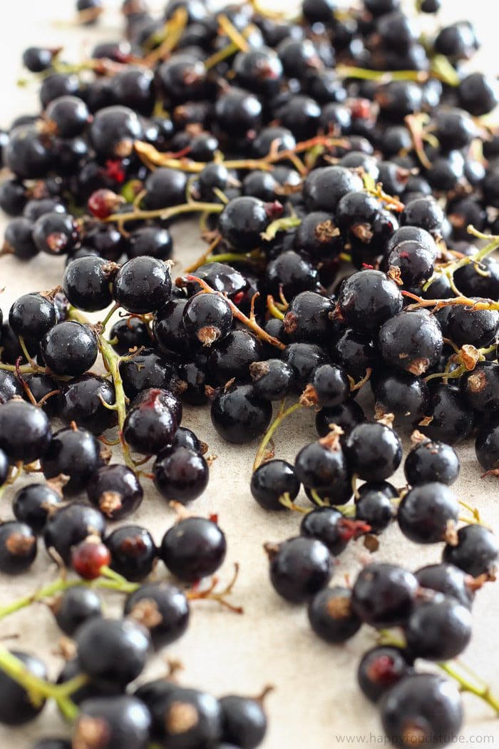 Fresh blackcurrants with stems still on, glossy and dark, spread out before cooking them down for ice cream.