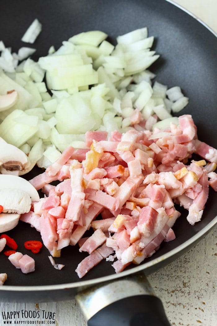 Bacon, onion, mushrooms and chili cooking in a frying pan.