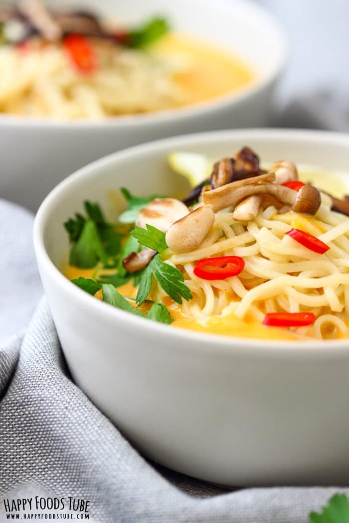 Spicy Thai Pumpkin Soup Pic Side view of Thai pumpkin soup with noodles, parsley and red chili in a white bowl.