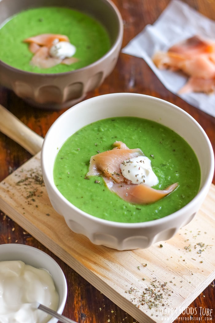 White and brown bowl with creamy green pea soup on the table