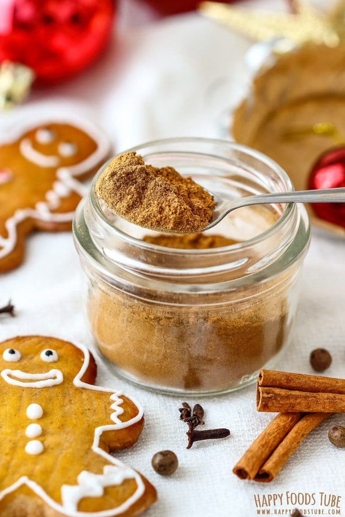 Glass jar of homemade gingerbread seasoning with cookies, cloves and cinnamon sticks.