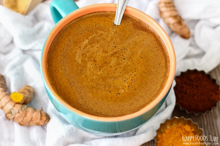 A cup of turmeric hot chocolate with a spoon.