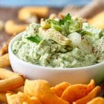 Green Artichoke Heart Dip on the white bowl with snacks