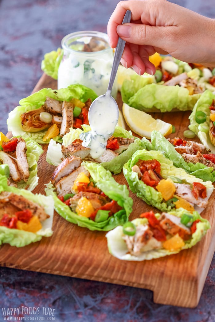 Topping Greek yogurt dressing on Mediterranean Chicken Lettuce Wraps