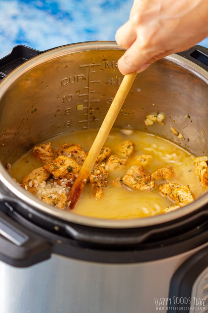 Julia stirs chicken and risotto rice in a pressure cooker with a wooden spoon.