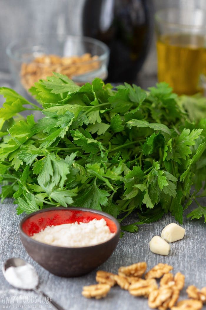Ingredients for parsley pesto with fresh parsley, walnuts, garlic, olive oil and Parmesan.