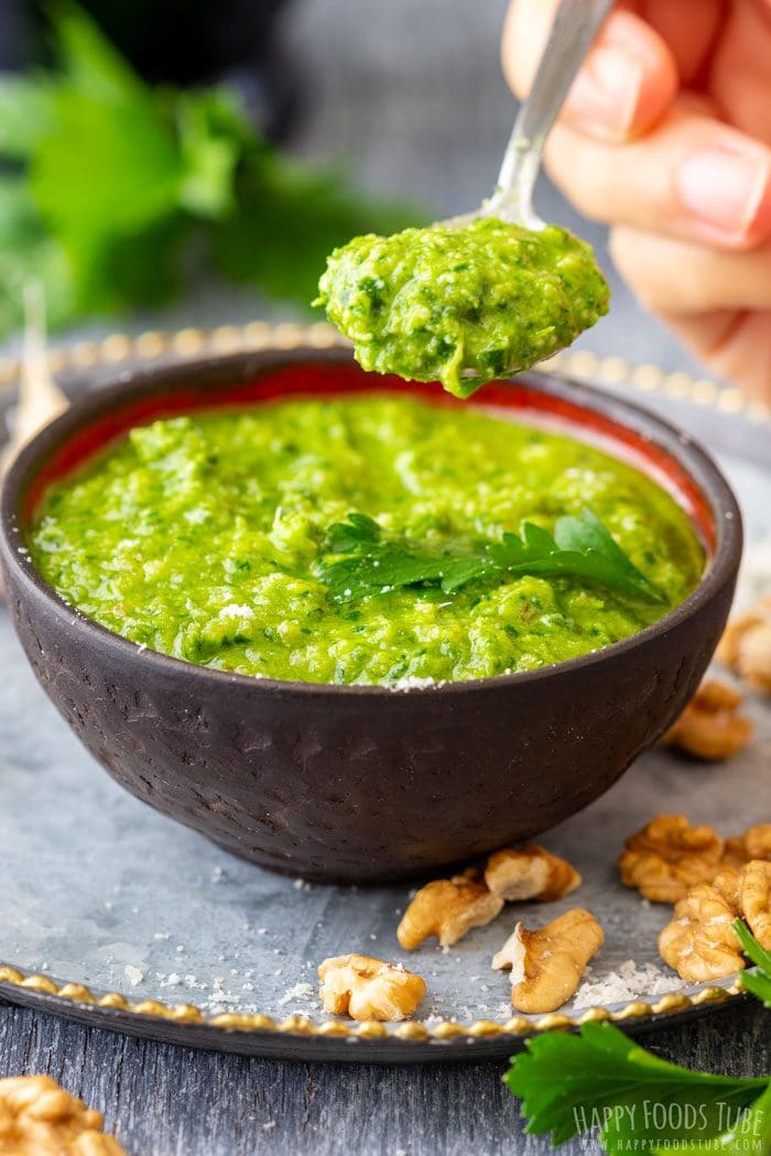 Spoonful of parsley pesto above a bowl showing the thick texture.