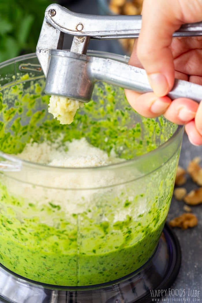 Pressed garlic added to pesto in a food processor.