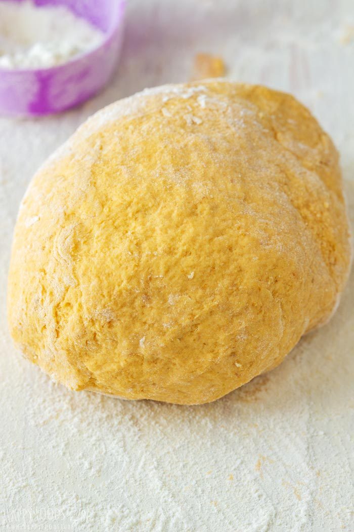 Pumpkin flatbread dough ball on a floured board.