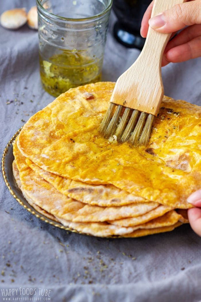 Brushing warm pumpkin flatbread with garlic and herb oil.