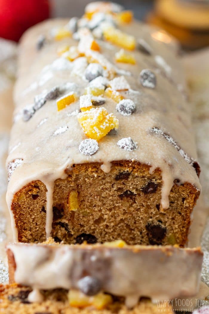 Close-up of iced gingerbread loaf slice showing chocolate chips and bits of candied orange.