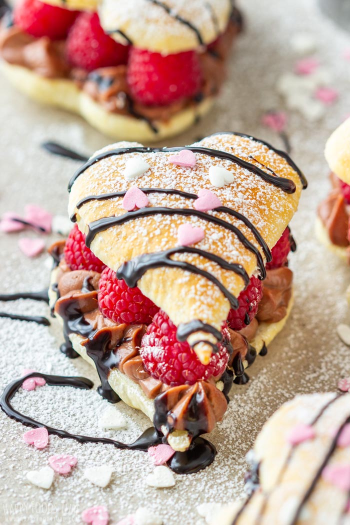 Heart-shaped puff pastry with raspberries, chocolate cream, powdered sugar and chocolate drizzle.