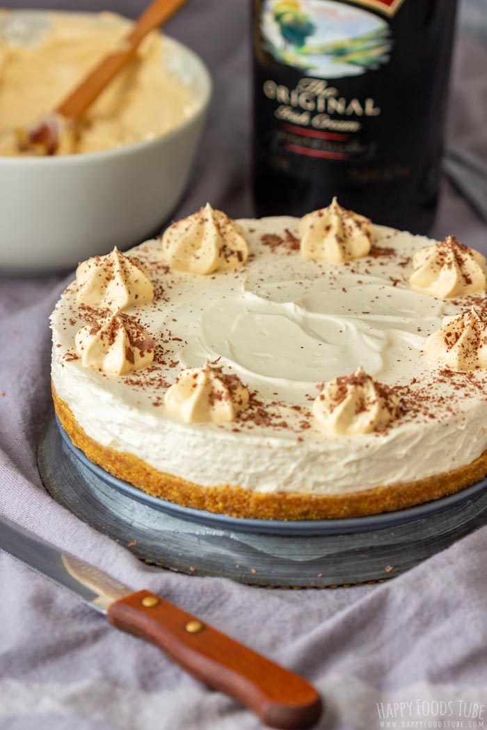 Whole Irish cream cheesecake topped with piped cream and chocolate shavings.
