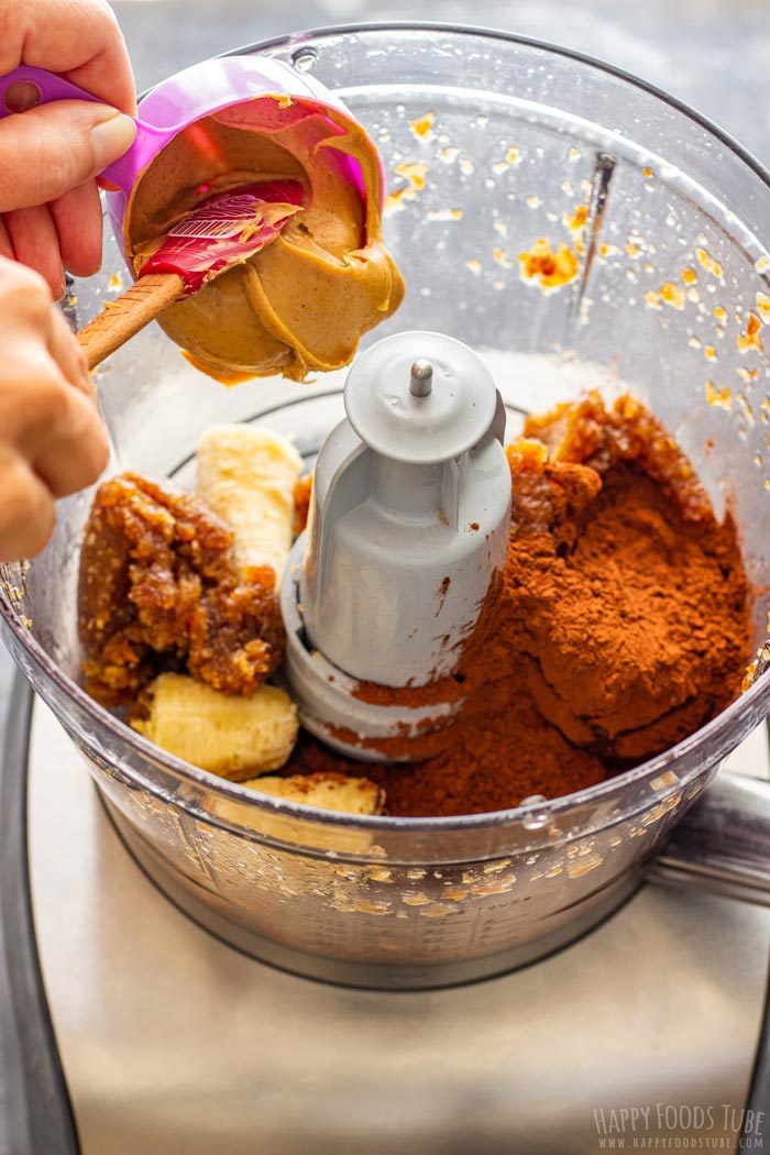Adding peanut butter to the food processor with cocoa powder, banana and the date mixture.