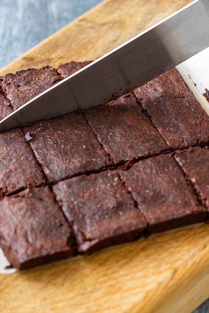 Baked brownies being cut into squares with a large knife.
