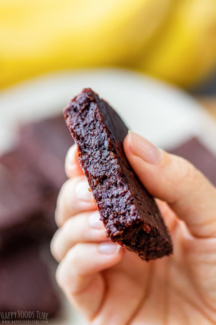 A fudgy date brownie held up to show the dense inside.
