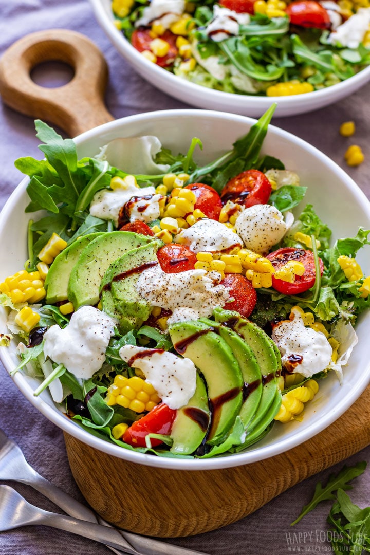 Burrata salad in a bowl with avocados, corn and tomatoes