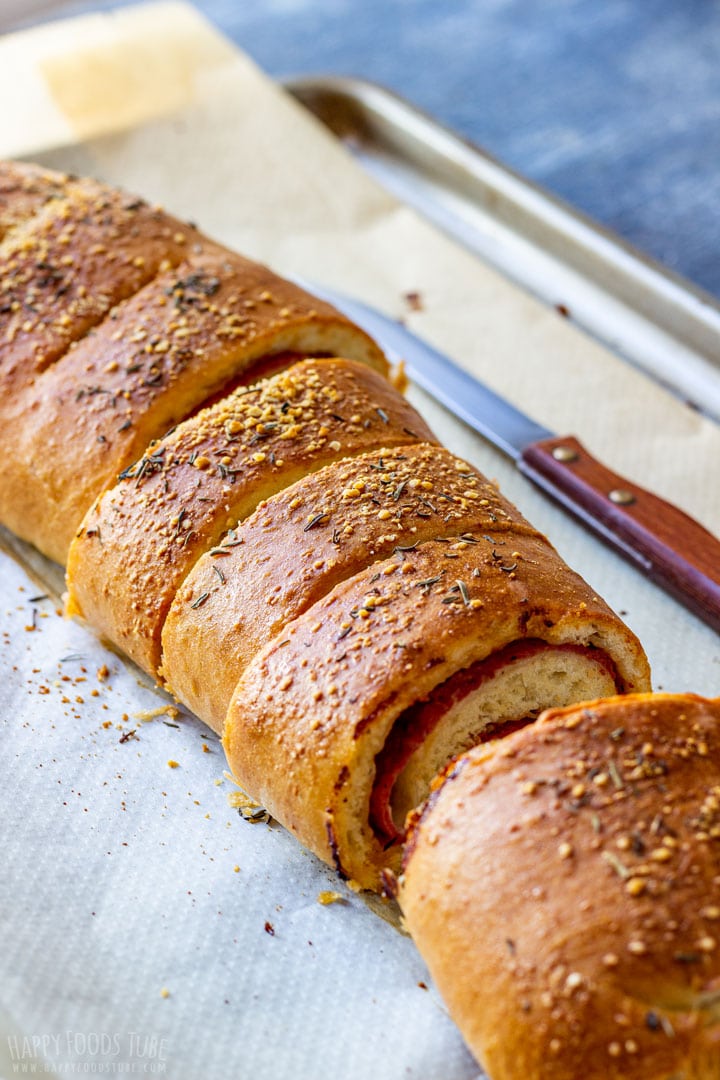 Baked roll sliced on a parchment-lined baking tray.