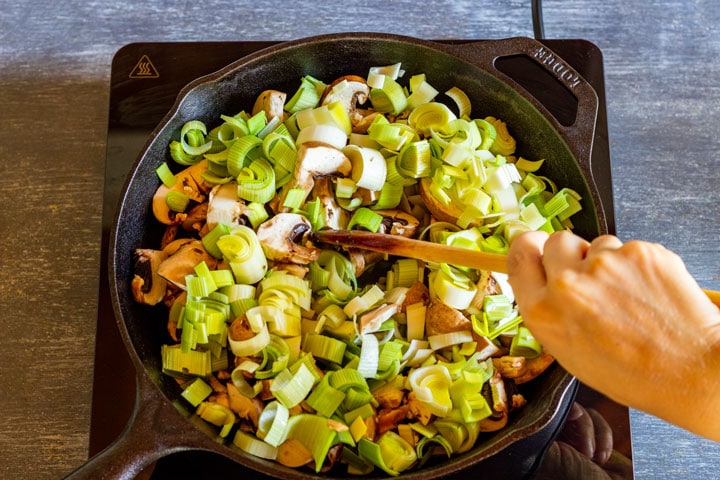 Cooking mushrooms and sliced leeks on a skillet.