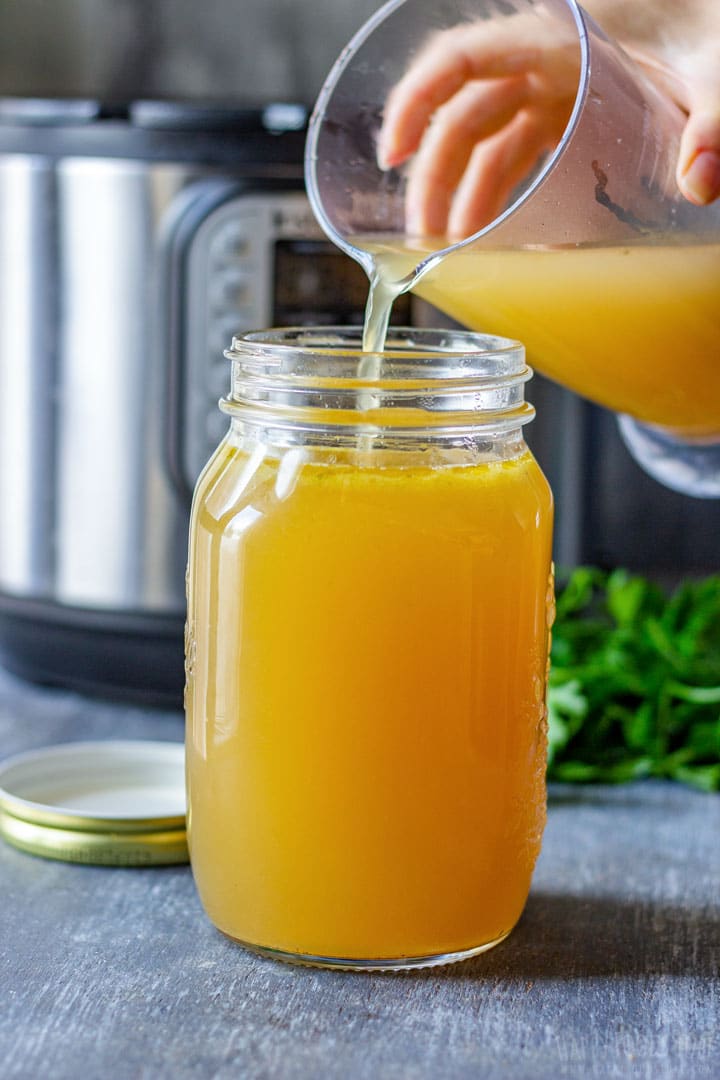 Pouring instant pot pressure cooker fish stock to the jars