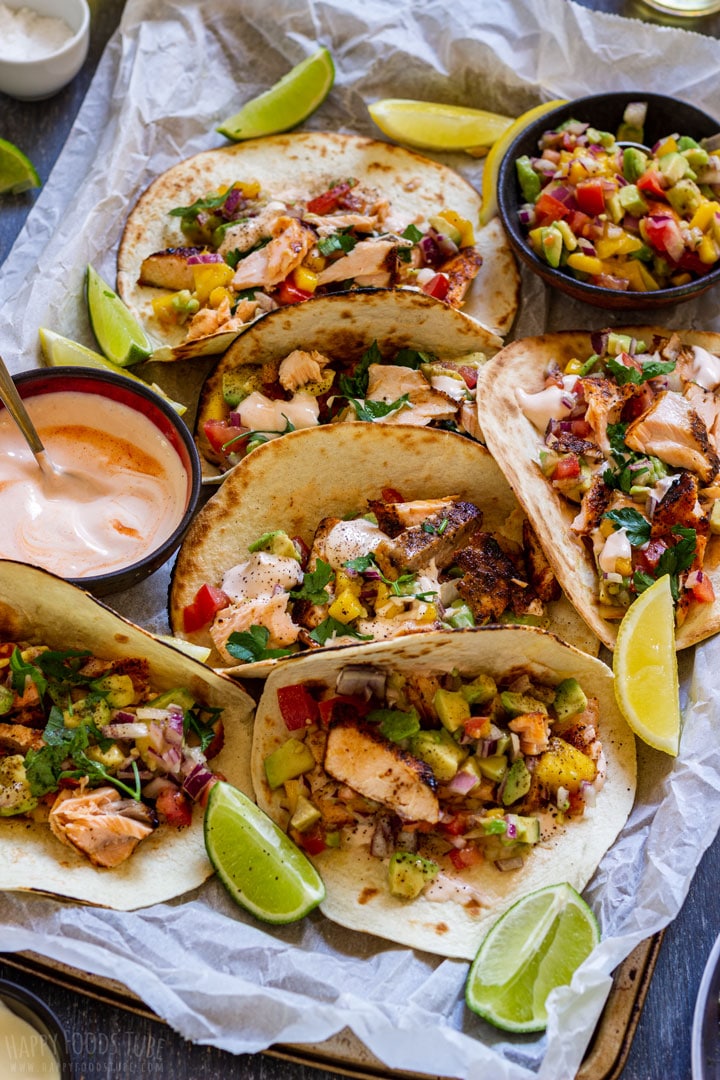 Salmon tacos on a tray with lime, mango and avocados