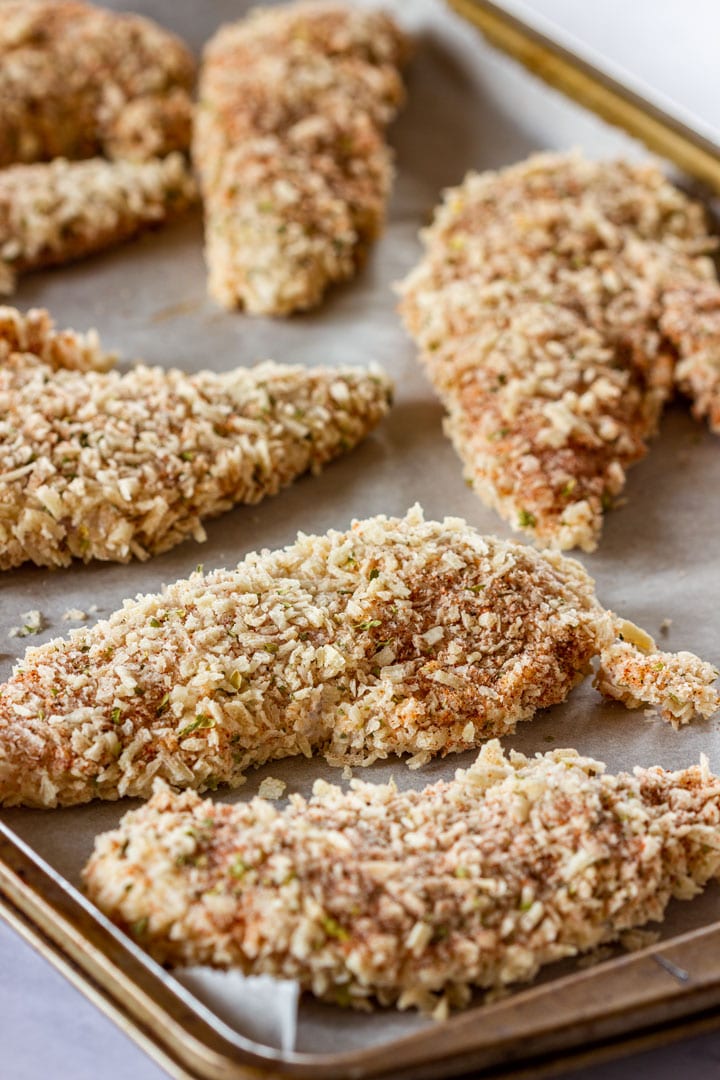 Uncooked chicken tenders coated with breadcrumbs and herbs