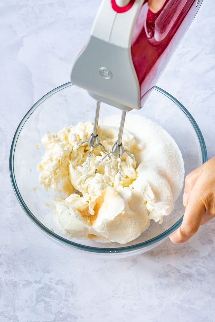 Mixing soft cheese and sugar with handmixer