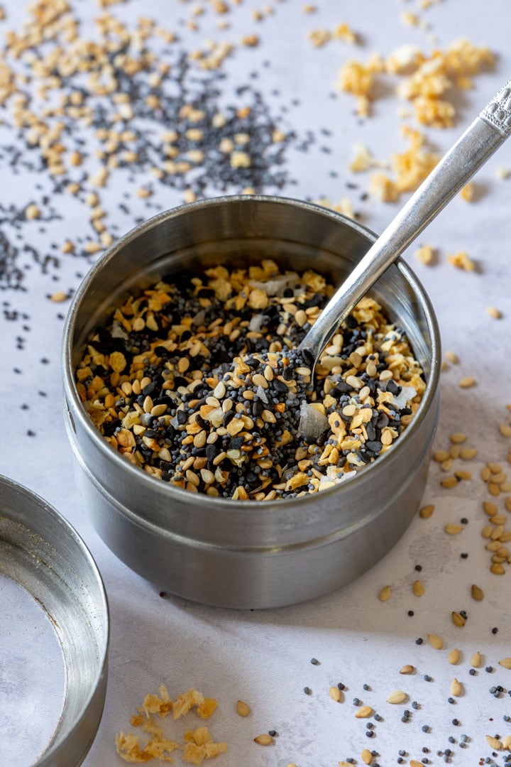 A metal container filled with homemade seasoning, with a spoon inside.