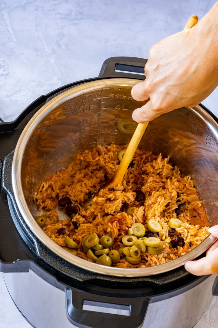 Mixing rice and beans with wooden spoon in an instant pot