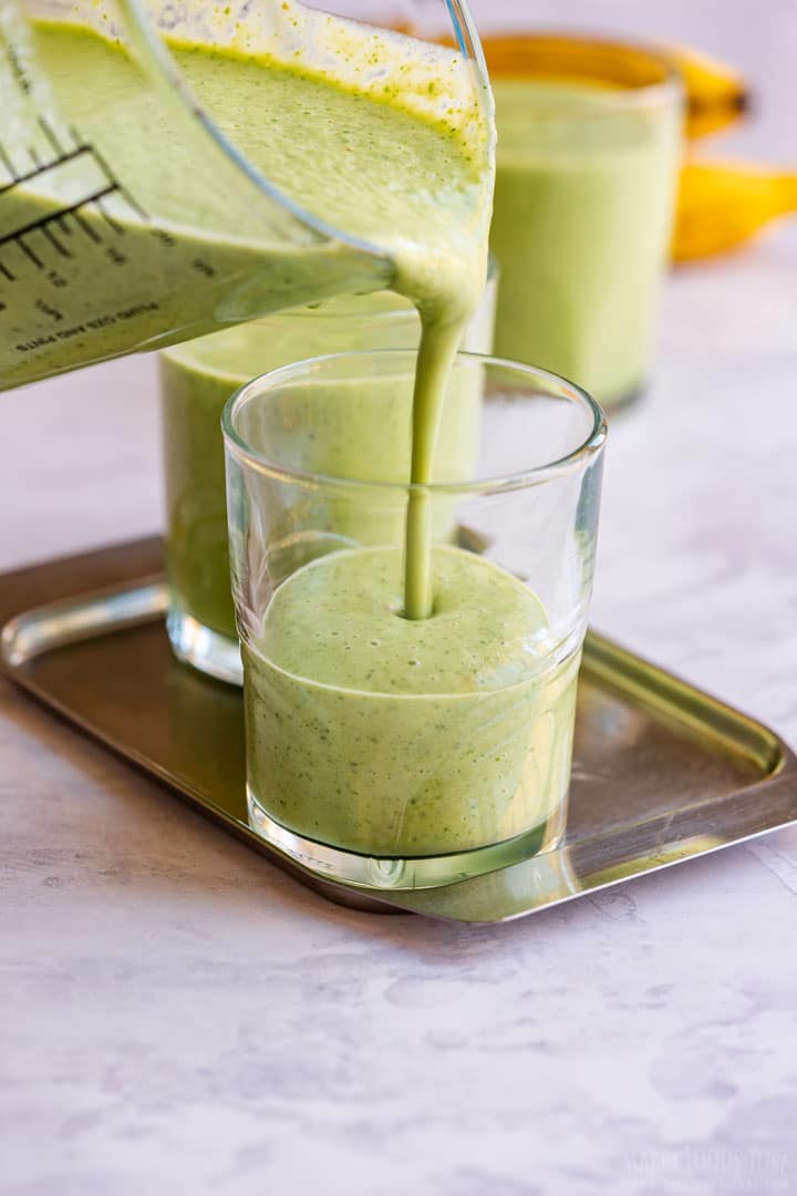 Pouring spinach and kale smoothie to the glass